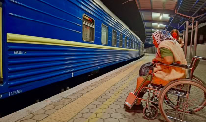 Жінка на колісному кріслі біля поїзда